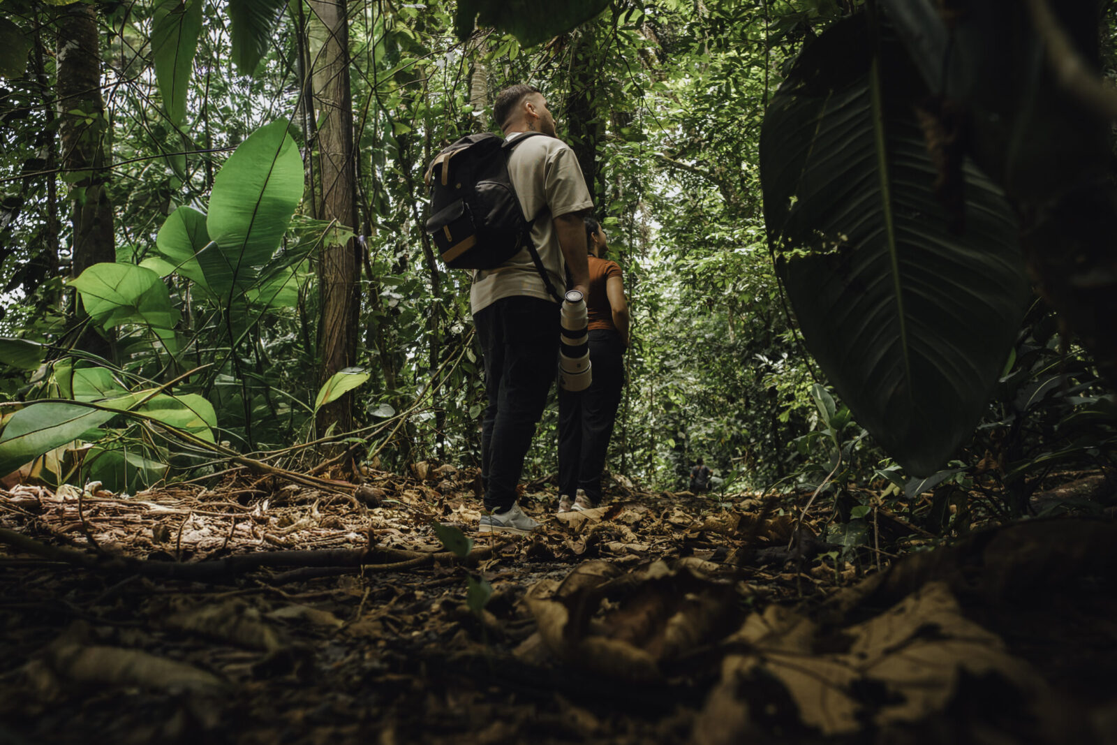 Young man with a camera walking on a rainforest path, ready for wildlife photography at Arenal Nature Trails, one of the top activities in Arenal Costa Rica.
