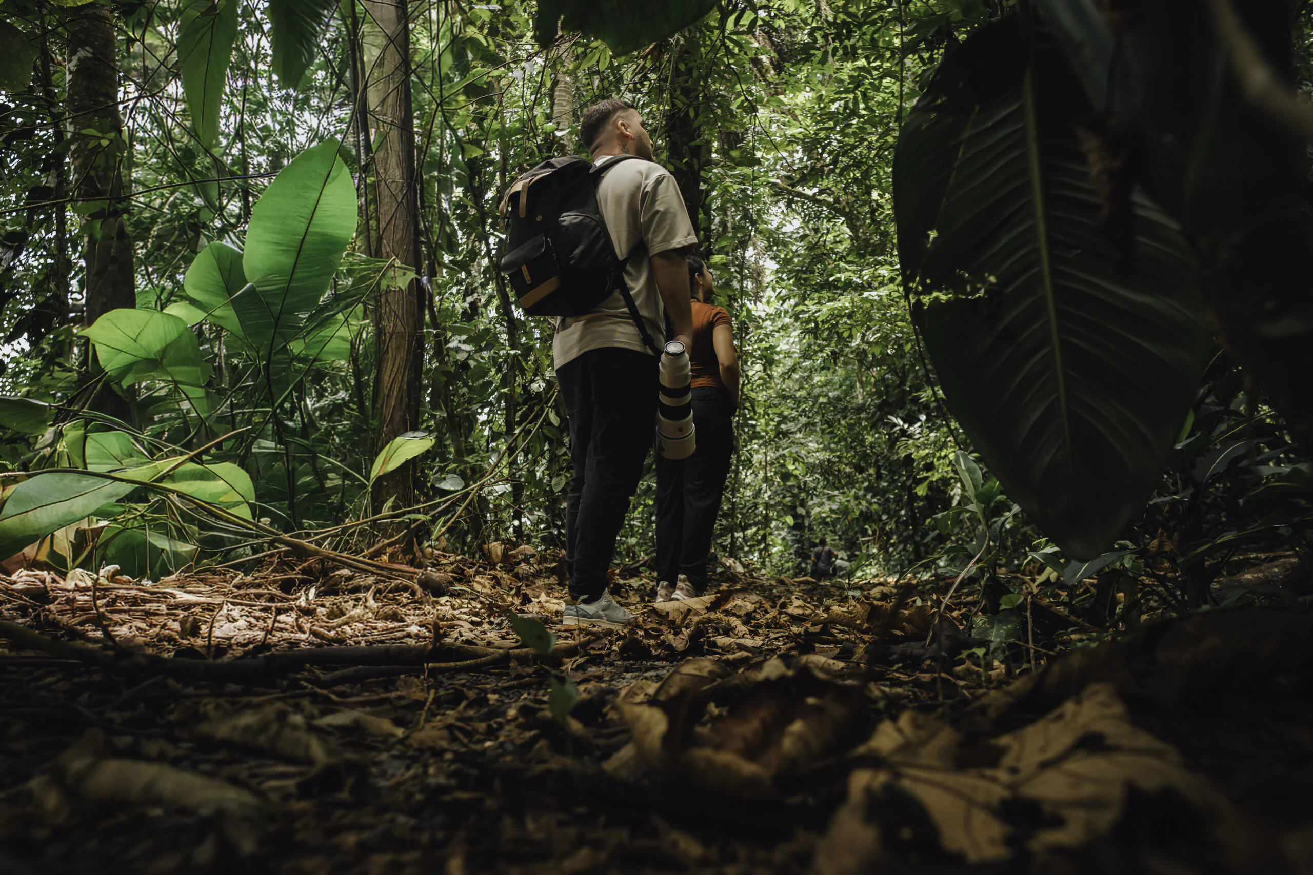 Young man with a camera walking on a rainforest path, ready for wildlife photography at Arenal Nature Trails, one of the top activities in Arenal Costa Rica.